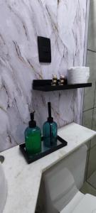 2 botellas verdes en un estante sobre un inodoro en un baño en Residencial suíte Arraial, en Arraial do Cabo