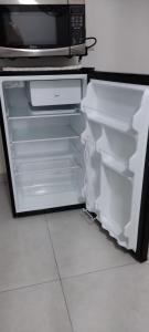 einen offenen Kühlschrank mit einer Mikrowelle darüber in der Unterkunft Residencial suíte Arraial in Arraial do Cabo