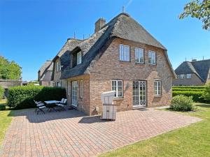 a large brick house with a thatched roof at Haus Carla Marie in Utersum