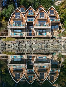 a house with a reflection in the water at Jade Resort-Oceanfront Suites in Gowlland Harbour in Heriot Bay