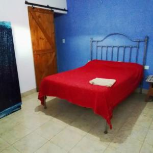 a blue bedroom with a red bed with a red blanket at Hostal El Buen Descanso in Rosario de Lerma