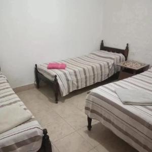 a room with three beds and a table at Hostal El Buen Descanso in Rosario de Lerma