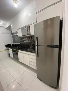 a stainless steel refrigerator in a kitchen with white cabinets at Praia de jangada 103 - barra de jangada recife in Recife