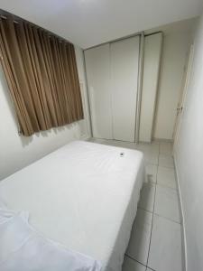 a white bed in a room with a window at Praia de jangada 103 - barra de jangada recife in Recife