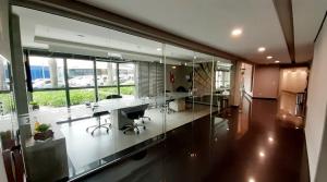 ein Büro mit Glaswänden, Schreibtischen und Stühlen in der Unterkunft Excelente Studio Completo Centro Curitiba - Ar Condicionado - 7th Avenue in Curitiba
