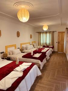 a group of four beds in a room at Hôtel Bia Besta in Boumalne Dades