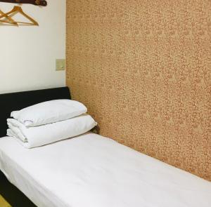 1 cama con 3 almohadas en una habitación en Guest House Izumi, en Izumisano