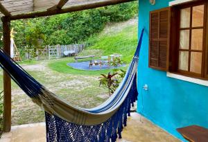 a blue house with a hammock in a yard at Vila Verde Perto in Lençóis