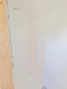 a shower in a bathroom with a white wall at Bus home wonderwander farmstay in Raworth