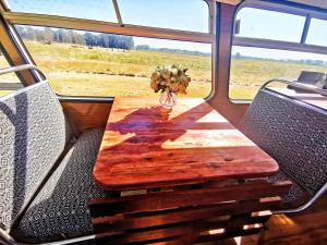 a wooden table sitting on a bus with chairs at Bus home wonderwander farmstay in Raworth