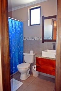 a bathroom with a toilet and a blue shower curtain at Hotel Cabinas Midey in Puntarenas