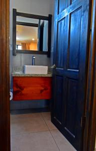 a bathroom with a sink and a blue door at Hotel Cabinas Midey in Puntarenas