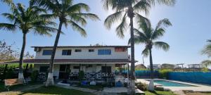 een huis met palmbomen en een zwembad bij Cabaña Playera Santa Veronica in Juan de Acosta