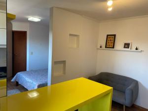 une chambre avec une table jaune et un lit dans l'établissement Studio Minimalista Região Central Residencial Padre Kolb 201C, à Joinville