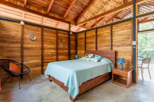 1 dormitorio con 1 cama en una habitación con paredes de madera en Nicoya Silvestre en Lepanto