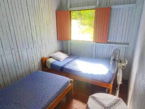 a small room with two beds and a window at Villa Montezuma Corcovado in Puerto Jiménez