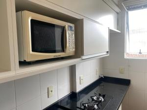 a microwave oven above a stove in a kitchen at Studio Minimalista Região Central Residencial Padre Kolb 201C in Joinville