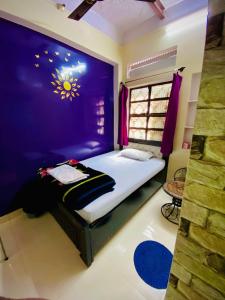 a bedroom with a bed with a purple wall at Marigold Guest House in Varanasi