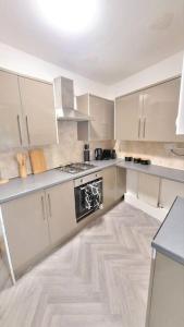 cocina con armarios blancos y estufa negra en 4 Double Bedroom House in Accrington sleeps 6, en Accrington