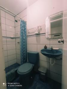 La salle de bains est pourvue de toilettes bleues et d'un lavabo. dans l'établissement Angello, à Lima