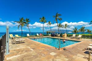 a pool with palm trees and the ocean in the background at Enjoy Your Oceanside Dream at Kihei Surfside in Wailea
