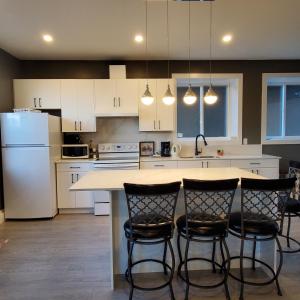 a kitchen with white cabinets and a island with bar stools at Licensed Mountain Retreat Garden House Near Heritage Park, Cultus Lake in Chilliwack