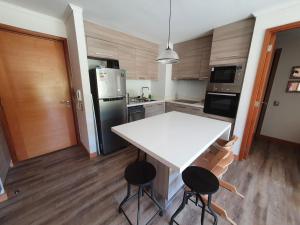 a kitchen with a white table and two stools at Acogedor Departamento a pasos del Lago Llanquihue in Puerto Varas