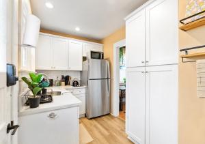 a kitchen with white cabinets and a stainless steel refrigerator at Cozy Oceanside Retreat-Walk to Beach! in Oceanside