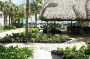 a patio with a straw umbrella and tables and palm trees at Tides Condominiums in Hollywood