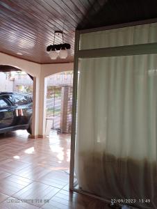 Cette chambre dispose d'une porte coulissante en verre avec un rideau. dans l'établissement Suites e Quartos em casa, à Foz do Iguaçu