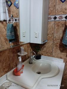 - un lavabo avec miroir et une bouteille de savon dans l'établissement Suites e Quartos em casa, à Foz do Iguaçu