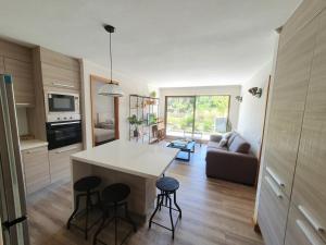 a kitchen and living room with a counter and stools at Acogedor Departamento a pasos del Lago Llanquihue in Puerto Varas