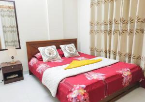 sypialnia z czerwono-białym łóżkiem z poduszkami w obiekcie Sweet & affordable stay in Dhaka w mieście Dhaka