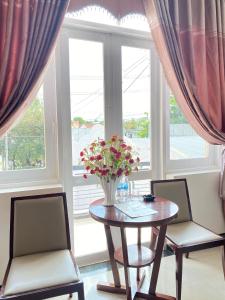 una mesa y dos sillas con un jarrón de flores. en Khách Sạn Sơn Hạ, en Kon Tum