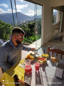mężczyzna siedzący przy stole z talerzem jedzenia w obiekcie Hotel Raio do Sol w mieście Ibicoara