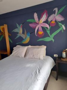 1 dormitorio con una pared azul con flores y 1 cama en Alojamiento Casa de T, en San Agustín