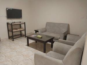 شقق نجوم الجزيرة للشقق المخدومة في تبوك: غرفة معيشة مع كرسيين وطاولة وتلفزيون
