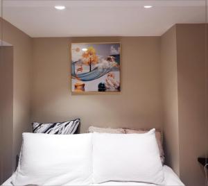 a bedroom with a white bed with a painting on the wall at toronto midtown spacious room in Toronto