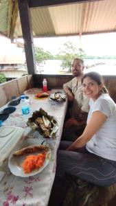 Hospedaje y tours Reina Arriera amazonas colombia في Macedonia: رجل وامرأة يجلسون على طاولة طعام