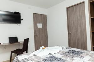 um quarto com uma cama, uma secretária e uma televisão em Hotel Galanni em Valledupar
