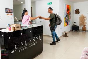 a man and a woman shaking hands at a counter at Hotel Galanni in Valledupar