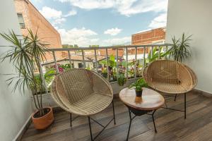 three chairs and a table on a balcony with plants at La Martina Hotel Boutique in Medellín