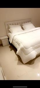 a white bed with white sheets and pillows at شاليه استكنان in Ash Shuqqah