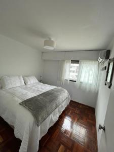 een witte slaapkamer met een bed en een houten vloer bij Apartamento recién renovado en Punta Carretas in Montevideo