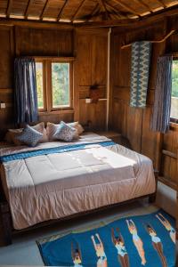 een groot bed in een kamer met 2 ramen bij Secret Joglo Lebih in Lebih