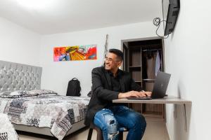 Hotel Galanni في فاليدوبار: رجل يجلس على طاولة مع جهاز كمبيوتر محمول