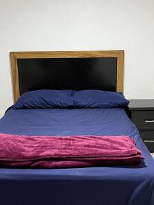 uma cama com lençóis e almofadas roxos e azuis em La ROBLEDA CASA DE CAMPO em Zapopan