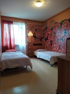 een slaapkamer met 2 bedden en een muurschildering van rozen bij Arthome Oxelösund in Oxelösund