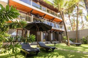 a patio with two chairs and an umbrella in front of a building at BK Beach Boutique Hotel - Hikkaduwa in Hikkaduwa