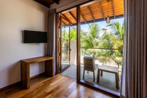 a room with a sliding glass door with a table and a chair at BK Beach Boutique Hotel - Hikkaduwa in Hikkaduwa